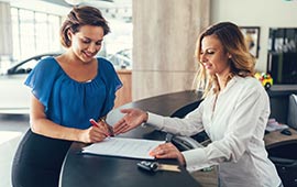 Woman filling out paperwork at car dealership.