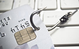 Credit card on fishing hook sitting on keyboard.